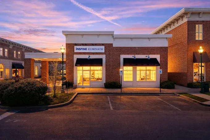 Inspine Chiropractic clinic exterior at dusk, with lit windows and cars parked in front.