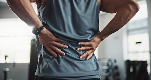 Fit Man With Back Injury - Preventing Sports Injuries With Chiropractic Check-ups